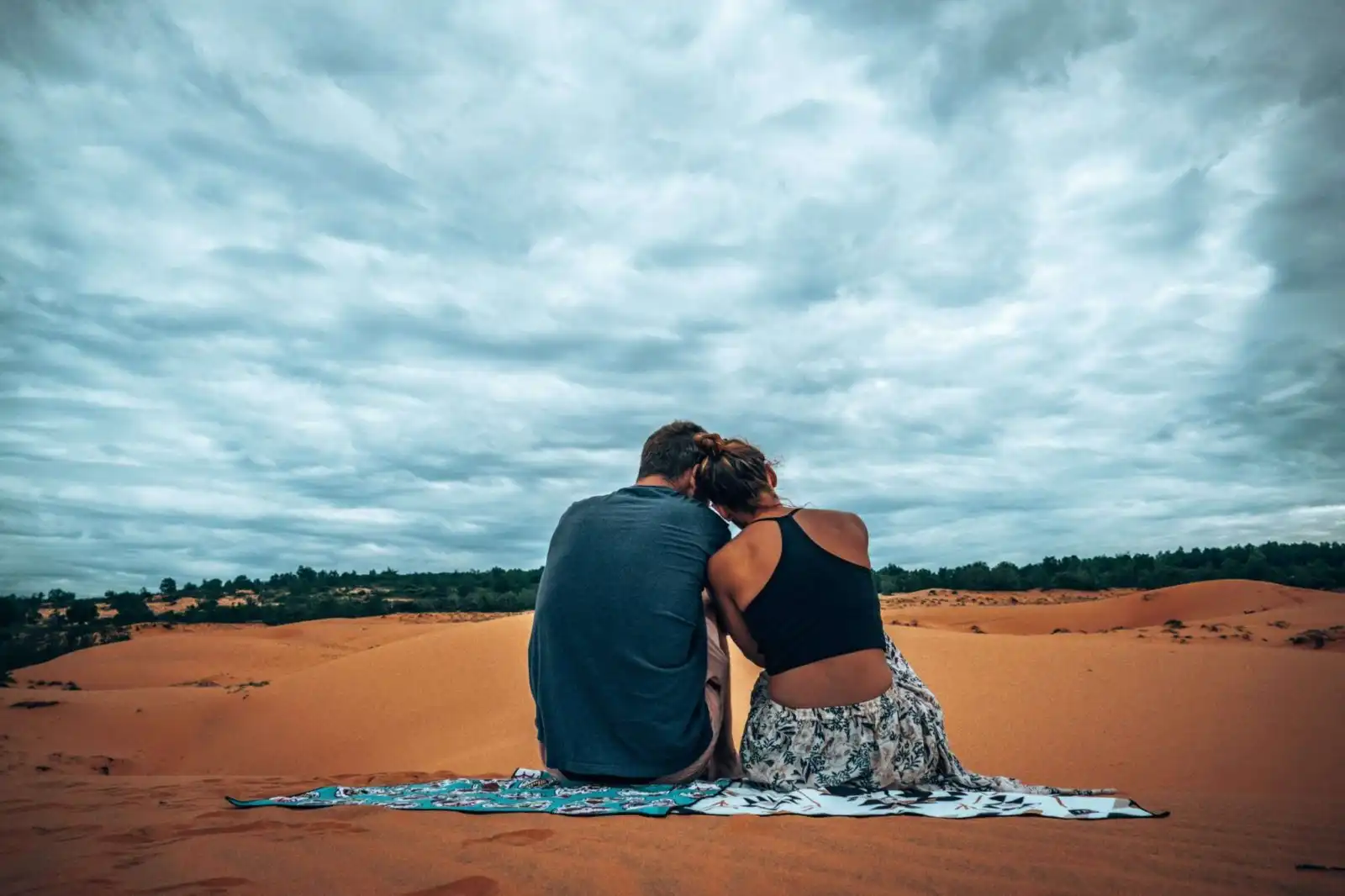 Couple sitting on the red sand dunes in Mui Ne Vietnam