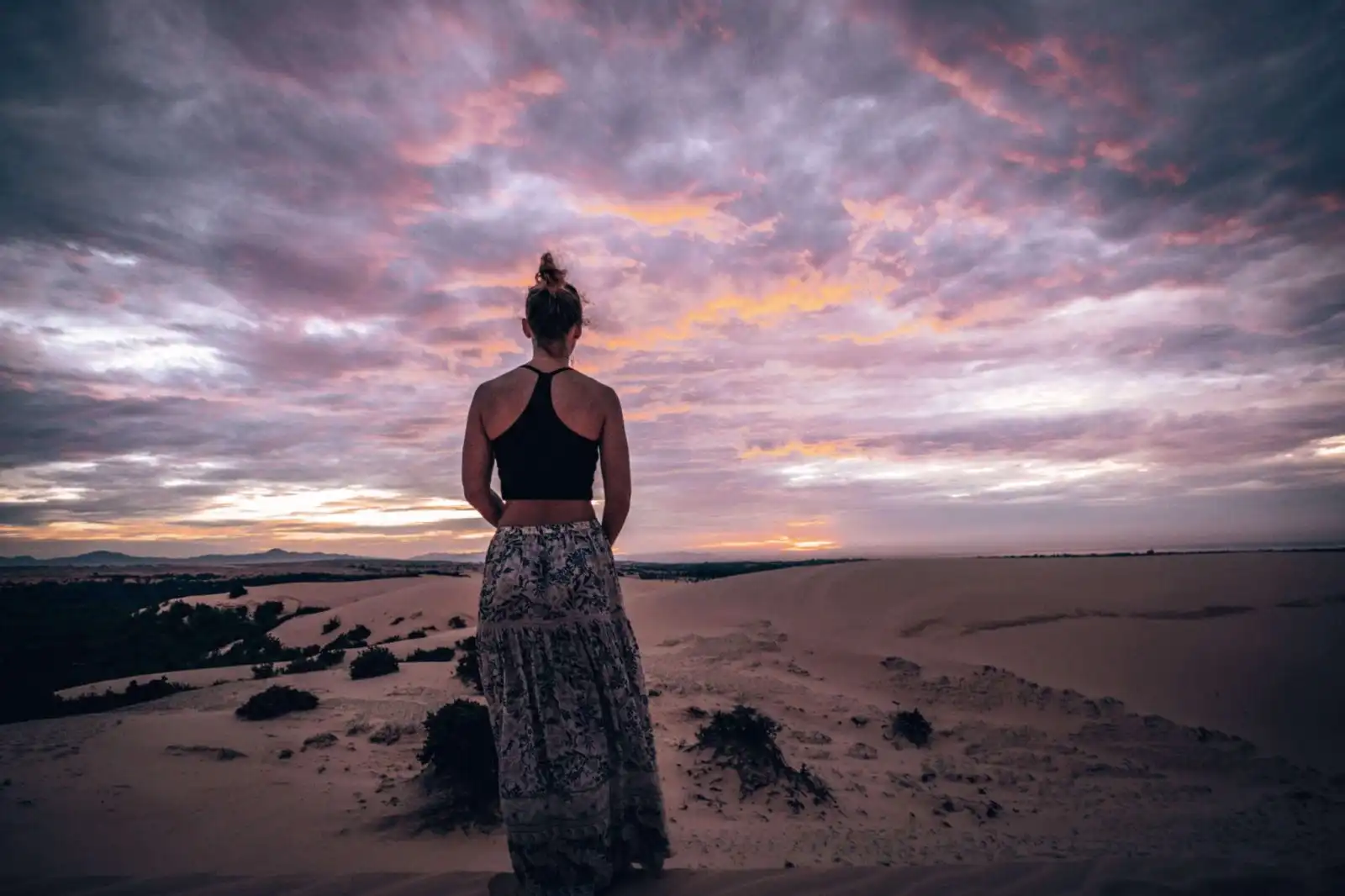 Girl looking out at white sand dunes in Mui Ne, at sunrise